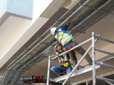 KAJANG, MALAYSIA - 16 Haziran 2017: Asılı elektrik metal kablo tepsisi döşeyen inşaat işçileri. 