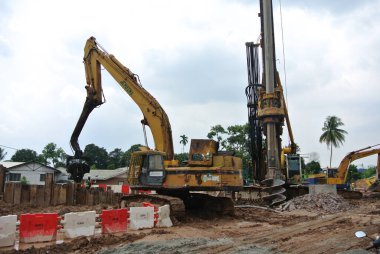 SELANGOR, MALAYSIA 25 Mart 2015: inşaat alanında çarşaf yığını cofferdam sürücü makine. Makine titreşimli hidrolik kolu kullanarak çarşaf yığınını yere itti. İşçi kontrolü. 