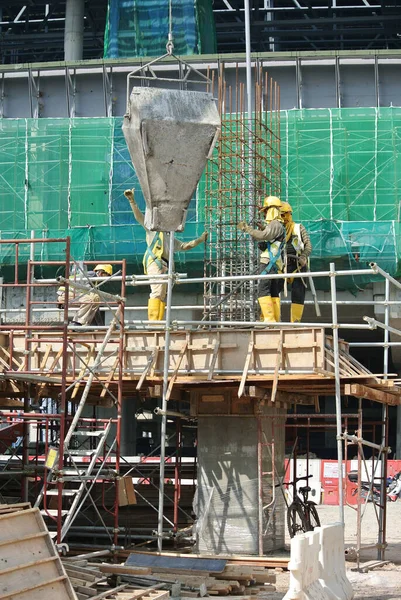マレーシア セランゴール2015年12月12日建設現場でコンクリート製のバケツを使ってコンクリートを木材の形に流し込む建設労働者のグループ — ストック写真