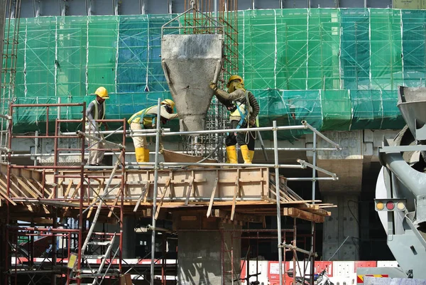マレーシア セランゴール2015年12月12日建設現場の木材工場にコンクリートバケツを使ってコンクリートを流し込む建設労働者のグループ — ストック写真