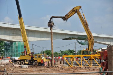 SELANGOR, MALAYSIA 25 Mart 2015: inşaat alanında çarşaf yığını cofferdam sürücü makine. Makine titreşimli hidrolik kolu kullanarak çarşaf yığınını yere itti. İşçi kontrolü. 