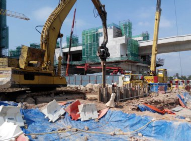 SELANGOR, MALAYSIA 25 Mart 2015: inşaat alanında çarşaf yığını cofferdam sürücü makine. Makine titreşimli hidrolik kolu kullanarak çarşaf yığınını yere itti. İşçi kontrolü. 