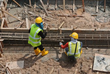 MALACCA, MALAYSIA -ECTOBER 13, 2015: Malacca, Malezya 'da inşaat alanında çelik takviye barı üreten inşaat işçileri. Destek çubuğu küçük bir kabloyla birbirine bağlanmış..  