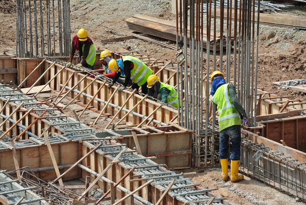 MALACCA, MALAYSIA -OCTOBER 13, 2015: Construction workers fabricating steel reinforcement bar at the construction site in Malacca, Malaysia. The reinforcement bar was tied together using a tiny cable.  