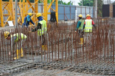 MALACCA, MALAYSIA -ECTOBER 13, 2015: Malacca, Malezya 'da inşaat alanında çelik takviye barı üreten inşaat işçileri. Destek çubuğu küçük kabloyla birbirine bağlanmıştı..  