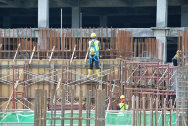 MALACCA, MALAYSIA - 29 Mart 2016: Malezya 'nın Malacca kentindeki inşaat alanında çelik takviye barı üreten inşaat işçileri. Destek çubuğu küçük bir kabloyla birbirine bağlanmış..  