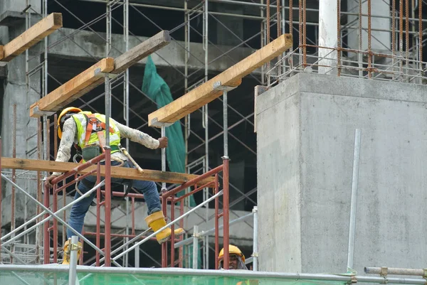 マレーシア セランゴール州 エイプリル社2016年5月5日 マレーシア セランゴールの建設現場に安全ハーネスを装着した建設労働者が高いレベルで足場を設置 — ストック写真