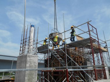 JOHOR, MALAYSIA - 13 Mart 2016: İnşaat alanındaki sütunlara beton kova kullanarak beton döken bir grup inşaat işçisi. 