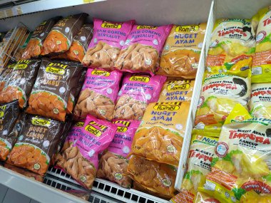 JOHOR, MALAYSIA -APRIL 22, 2021: Dev süpermarketin içindeki soğutucu buzdolabına yerleştirilmiş çeşitli markalarda tavuk nugget ticari ambalajına odaklanmış.