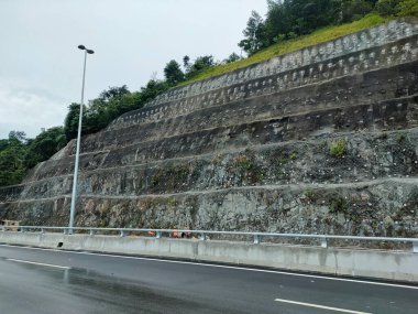 Toprak Çivi ve beton istinat duvarı. Bu, doğal ya da kazılmış yamaçlarda kullanılabilen bir yer dengeleme tekniğidir. Çelik çubukların eğimli bir yüze yerleştirilmesi için delme delikleri içeriyor.. 