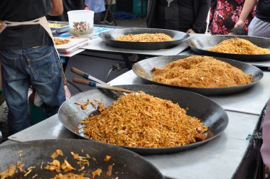 Malezya sokak yemeği Mee Dulang. Erişteler gece pazarında ya da sokakta büyük miktarlarda büyük tavalarda pişirilir. Paketlerde ucuza satılıyor..
