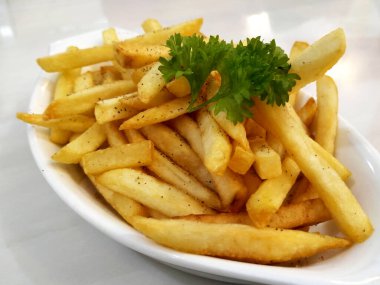 KUALA LUMPUR, MALAYSIA - 2 Şubat 2021: Beyaz bir tabağa yerleştirilmiş patates kızartmalarına odaklanmış. Müşterilere servis edilmeye hazır.