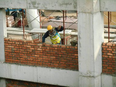 JOHOR, MALAYSIA -13 Ocak 2017: Tuğlacı inşaat alanında inşaat duvarları oluşturmak için kil tuğlalar döşedi. 
