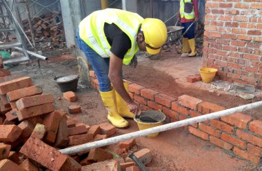 JOHOR, MALAYSIA -13 Ocak 2017: Tuğlacı inşaat alanında inşaat duvarları oluşturmak için kil tuğlalar döşedi. 