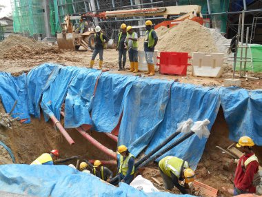 SELANGOR, MALAYSIA -HAZİRAN 03, 2017: yeraltı araçları ve drenaj siperleri. İnşaat işçileri makineleri kullanarak hendek kazıyor ve yeraltında beton kanalizasyonu ve elektrik tesisatını kullanıyor..  