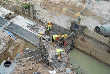 SELANGOR, MALAYSIA - 02 Aralık 2016: İnşaat işçileri inşaat alanında inşaat öncesi beton drenaj döşüyorlar. 