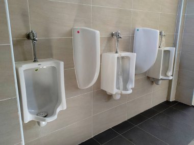 SELANGOR, MALAYSIA - 2 Mart 2022: Erkekler umumi tuvaletlerine tuvalet monte edilir. Kullanıcılarına mahremiyet sağlamak için bölen bir duvarla ayrılmış.