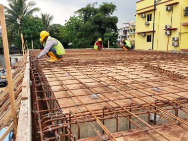 JOHOR, MALAYSIA - 30 Mart 2021: İnşaat işçileri bir inşaat sahasında çalışıyor. Güvenlik kaskı ve güvenlik yelekleri gibi güvenlik ekipmanları giymeleri gerekiyor.