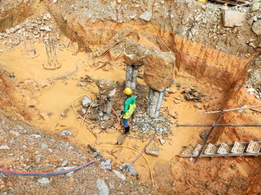 JOHOR, MALAYSIA - 30 Mart 2021: İnşaat işçileri bir inşaat sahasında çalışıyor. Güvenlik kaskı ve güvenlik yelekleri gibi güvenlik ekipmanları giymeleri gerekiyor.