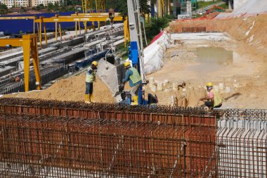 SELANGOR, MALAYSIA -5 Nisan 2021: İnşaat işçileri bir inşaat sahasında çalışıyorlar. Güvenlik kaskı ve güvenlik yelekleri gibi güvenlik ekipmanları giymeleri gerekiyor.
