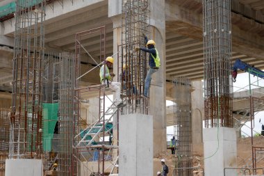 SELANGOR, MALAYSIA -5 Nisan 2021: İnşaat işçileri bir inşaat sahasında çalışıyorlar. Güvenlik kaskı ve güvenlik yelekleri gibi güvenlik ekipmanları giymeleri gerekiyor.