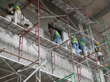 SELANGOR, MALAYSIA -5 Nisan 2021: İnşaat işçileri bir inşaat sahasında çalışıyorlar. Güvenlik kaskı ve güvenlik yelekleri gibi güvenlik ekipmanları giymeleri gerekiyor.