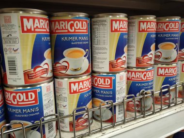 SELANGOR, MALAYSIA -4 Nisan 2022: tatlandırılmış krema ve buharlaştırılmış süt kutularda paketlendi. Süpermarketin içindeki rafta satılık. Ana bileşen palmiye yağı tohumlarından yapılır..