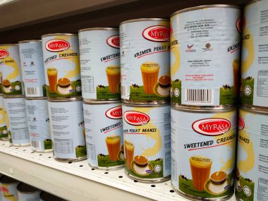 SELANGOR, MALAYSIA -4 Nisan 2022: tatlandırılmış krema ve buharlaştırılmış süt kutularda paketlendi. Süpermarketin içindeki rafta satılık. Ana bileşen palmiye yağı tohumlarından yapılır..