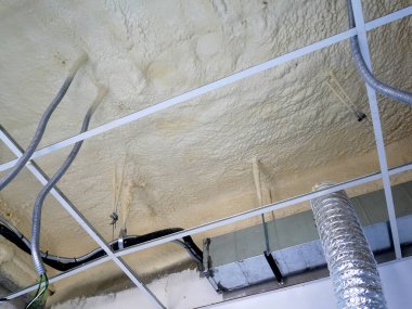 SELANGOR, MALAYSIA - 10 Mart 2022: poliüretan yalıtım köpüğü püskürtülmüş ve beton levhaların altındaki yüzeyi kaplamıştır. Binanın termal yalıtımı için bir katman görevi görür..