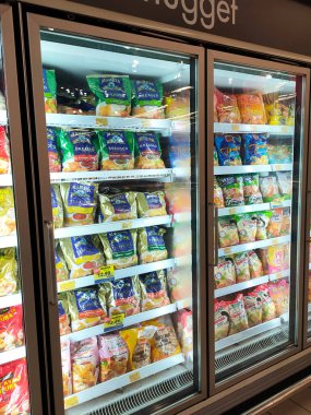 SELANGOR, MALAYSIA - 15 Nisan 2021: Dev süpermarketteki soğutucu buzdolabının içine yerleştirilmiş çeşitli markalarda tavuk nugget ticari ambalajına odaklanmış.