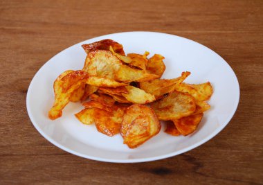 Kurutulmuş ve kızarmış kaju dilimleri ile baharatlı biber sosu karıştırılmış beyaz tabakta ahşap dokuda izole edilmiş. Bu yerel Malezya geleneksel abur cuburu Kerepek Ubi olarak da bilinir.. 