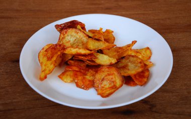 Kurutulmuş ve kızarmış kaju dilimleri ile baharatlı biber sosu karıştırılmış beyaz tabakta ahşap dokuda izole edilmiş. Bu yerel Malezya geleneksel abur cuburu Kerepek Ubi olarak da bilinir.. 