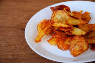 Kurutulmuş ve kızarmış kaju dilimleri ile baharatlı biber sosu karıştırılmış beyaz tabakta ahşap dokuda izole edilmiş. Bu yerel Malezya geleneksel abur cuburu Kerepek Ubi olarak da bilinir.. 