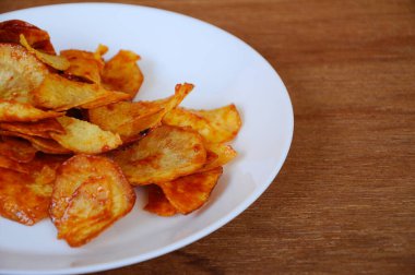 Kurutulmuş ve kızarmış kaju dilimleri ile baharatlı biber sosu karıştırılmış beyaz tabakta ahşap dokuda izole edilmiş. Bu yerel Malezya geleneksel abur cuburu Kerepek Ubi olarak da bilinir.. 