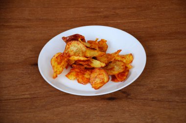 Kurutulmuş ve kızarmış kaju dilimleri ile baharatlı biber sosu karıştırılmış beyaz tabakta ahşap dokuda izole edilmiş. Bu yerel Malezya geleneksel abur cuburu Kerepek Ubi olarak da bilinir.. 