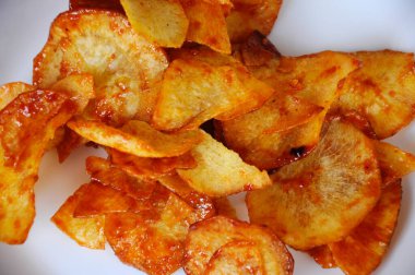 Kurutulmuş ve kızarmış kaju dilimleri ile baharatlı biber sosu karıştırılmış beyaz tabakta ahşap dokuda izole edilmiş. Bu yerel Malezya geleneksel abur cuburu Kerepek Ubi olarak da bilinir.. 