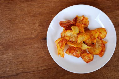 Kurutulmuş ve kızarmış kaju dilimleri ile baharatlı biber sosu karıştırılmış beyaz tabakta ahşap dokuda izole edilmiş. Bu yerel Malezya geleneksel abur cuburu Kerepek Ubi olarak da bilinir.. 