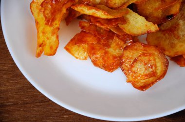 Kurutulmuş ve kızarmış kaju dilimleri ile baharatlı biber sosu karıştırılmış beyaz tabakta ahşap dokuda izole edilmiş. Bu yerel Malezya geleneksel abur cuburu Kerepek Ubi olarak da bilinir.. 