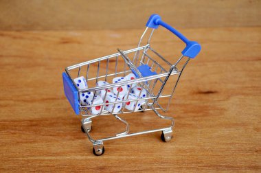 Oyuncak alışveriş arabasındaki beyaz zarlar ahşap dokuda. 