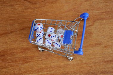 Oyuncak alışveriş arabasındaki beyaz zarlar ahşap dokuda. 