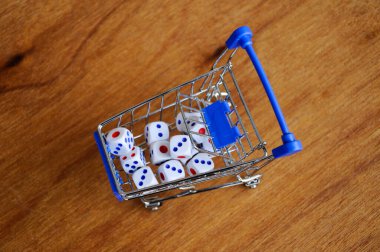 Oyuncak alışveriş arabasındaki beyaz zarlar ahşap dokuda. 