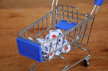 Oyuncak alışveriş arabasındaki beyaz zarlar ahşap dokuda. 