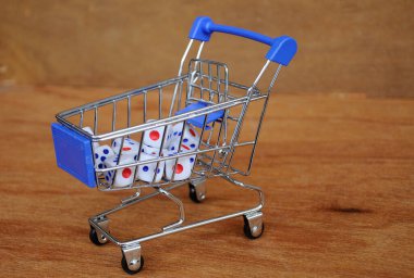 Oyuncak alışveriş arabasındaki beyaz zarlar ahşap dokuda. 