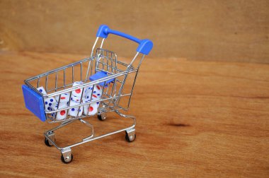 Oyuncak alışveriş arabasındaki beyaz zarlar ahşap dokuda. 