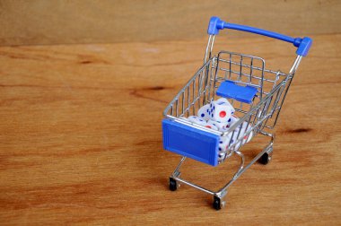 Oyuncak alışveriş arabasındaki beyaz zarlar ahşap dokuda. 