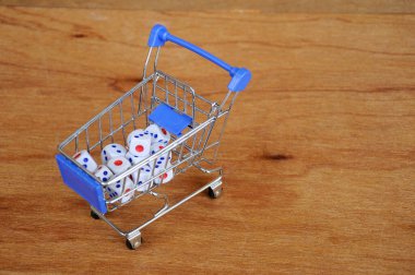 Oyuncak alışveriş arabasındaki beyaz zarlar ahşap dokuda. 