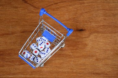 Oyuncak alışveriş arabasındaki beyaz zarlar ahşap dokuda. 