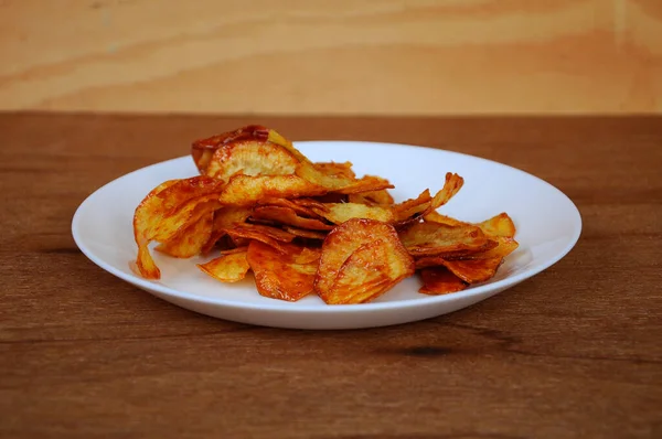 Kurutulmuş ve kızarmış kaju dilimleri ile baharatlı biber sosu karıştırılmış beyaz tabakta ahşap dokuda izole edilmiş. Bu yerel Malezya geleneksel abur cuburu Kerepek Ubi olarak da bilinir.. 