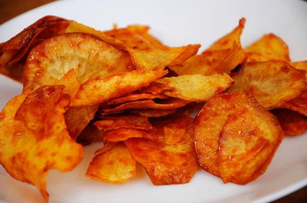 Kurutulmuş ve kızarmış kaju dilimleri ile baharatlı biber sosu karıştırılmış beyaz tabakta ahşap dokuda izole edilmiş. Bu yerel Malezya geleneksel abur cuburu Kerepek Ubi olarak da bilinir.. 