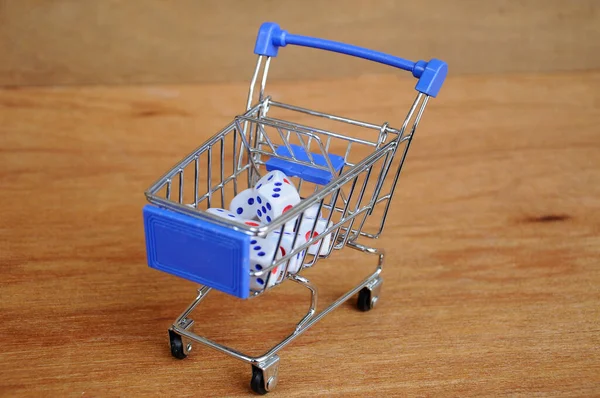Oyuncak alışveriş arabasındaki beyaz zarlar ahşap dokuda. 
